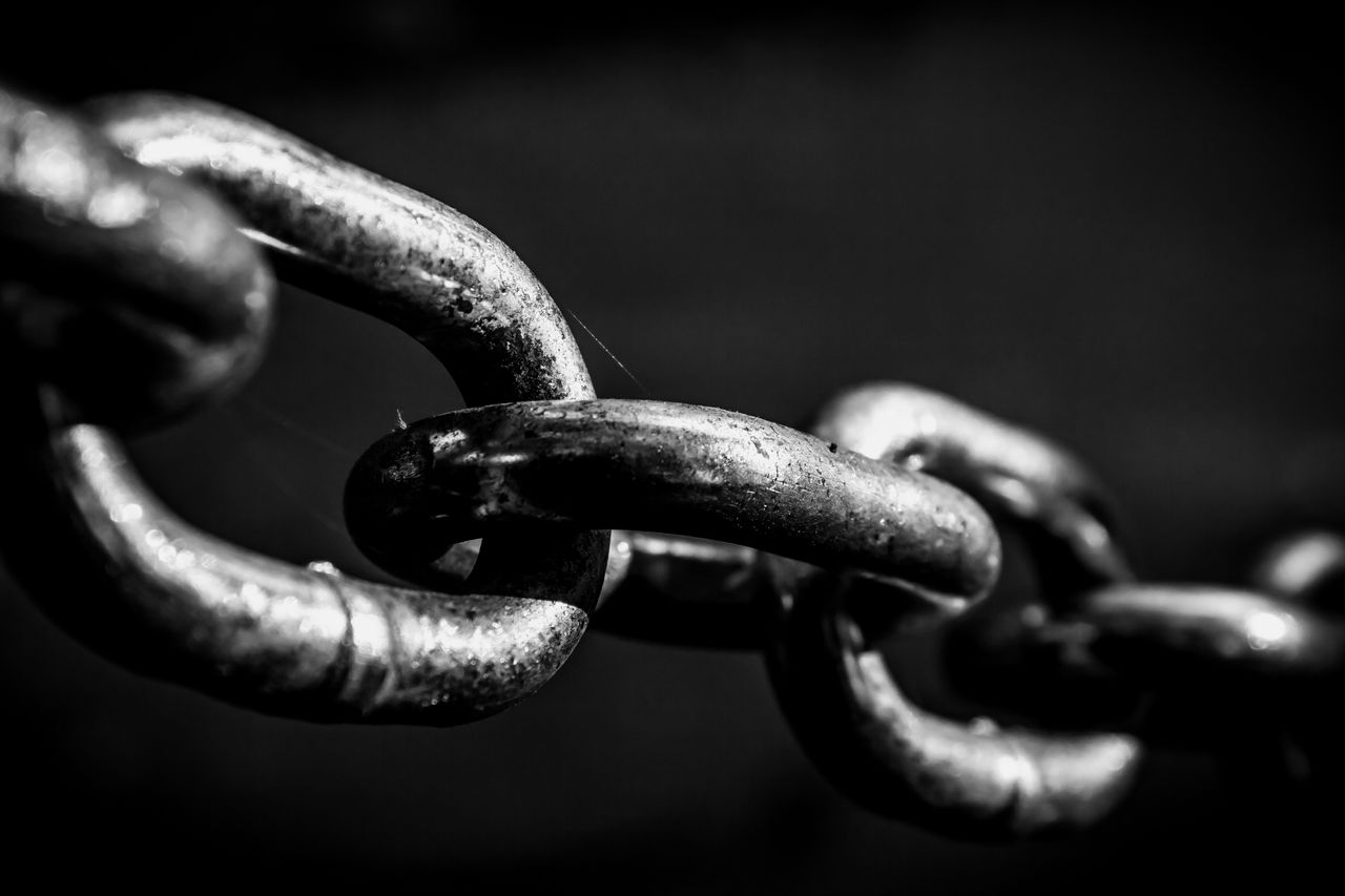 Black and white close up shot to a stretched chain.